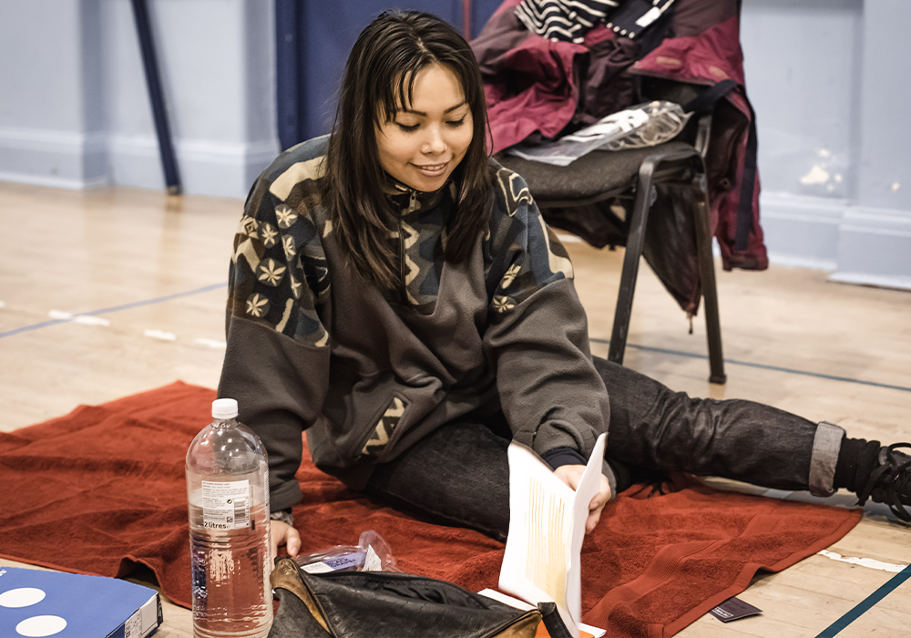 Actor Siu-See Hung sat on the floor looking through a script.