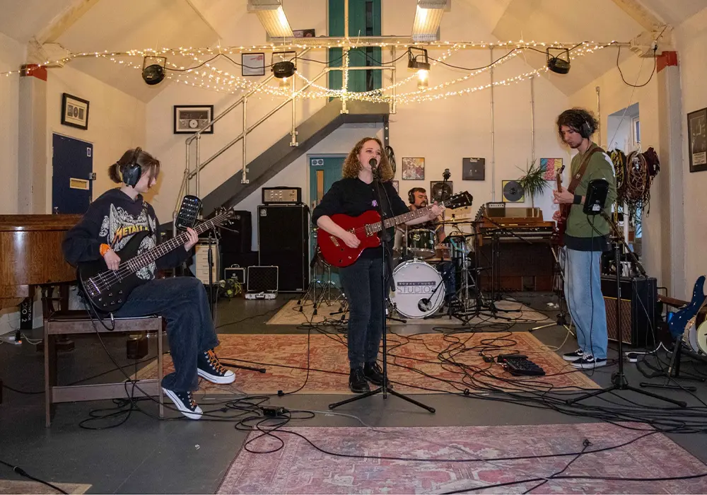 Four musicians recording a song in a studio space.