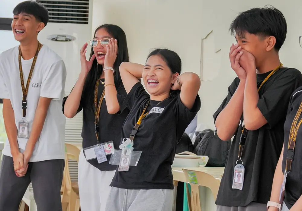 A workshop with young people from the Philippines. Four people laughing.